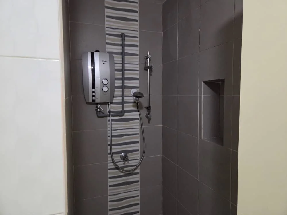 Bathroom features: shower with glass enclosure, wall-mounted shower head, handheld shower, chrome faucet, tiled walls with decorative strip, dark grey wall tiles, built-in niche for toiletries, water heater, sliding shower door; style: modern.